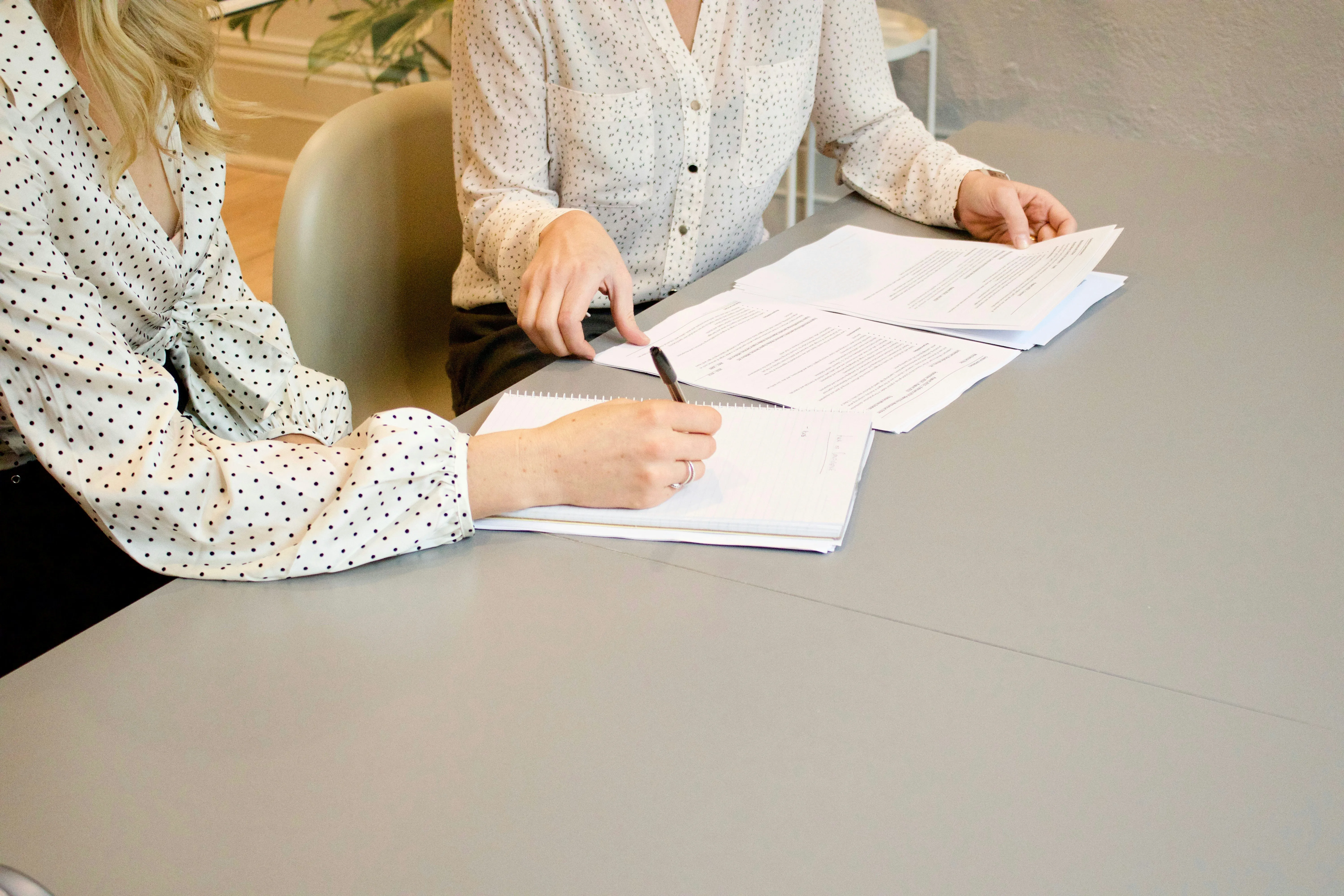 Zwei Beraterinnen am Tisch beim Durchgehen von Unterlagen - Mandatsbesprechung