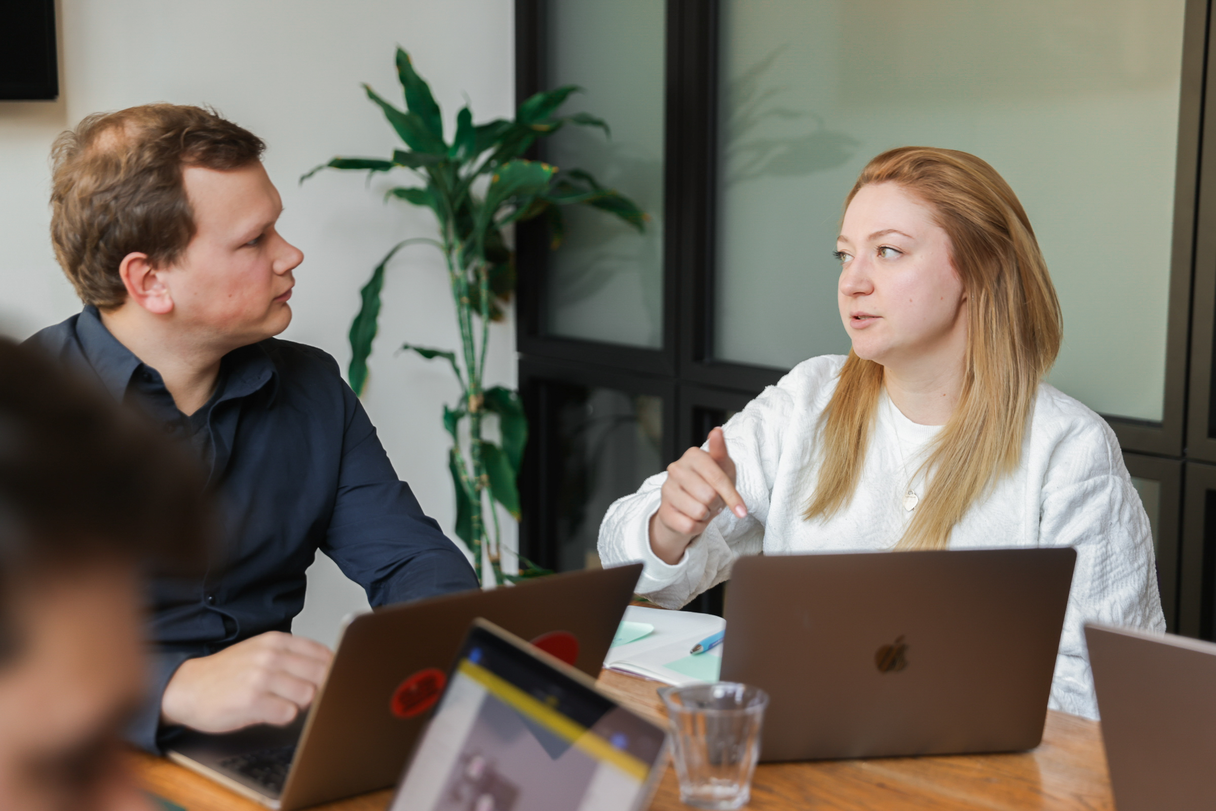 Zwei Fidarion-Teammitglieder im Gespräch über Laptops hinweg